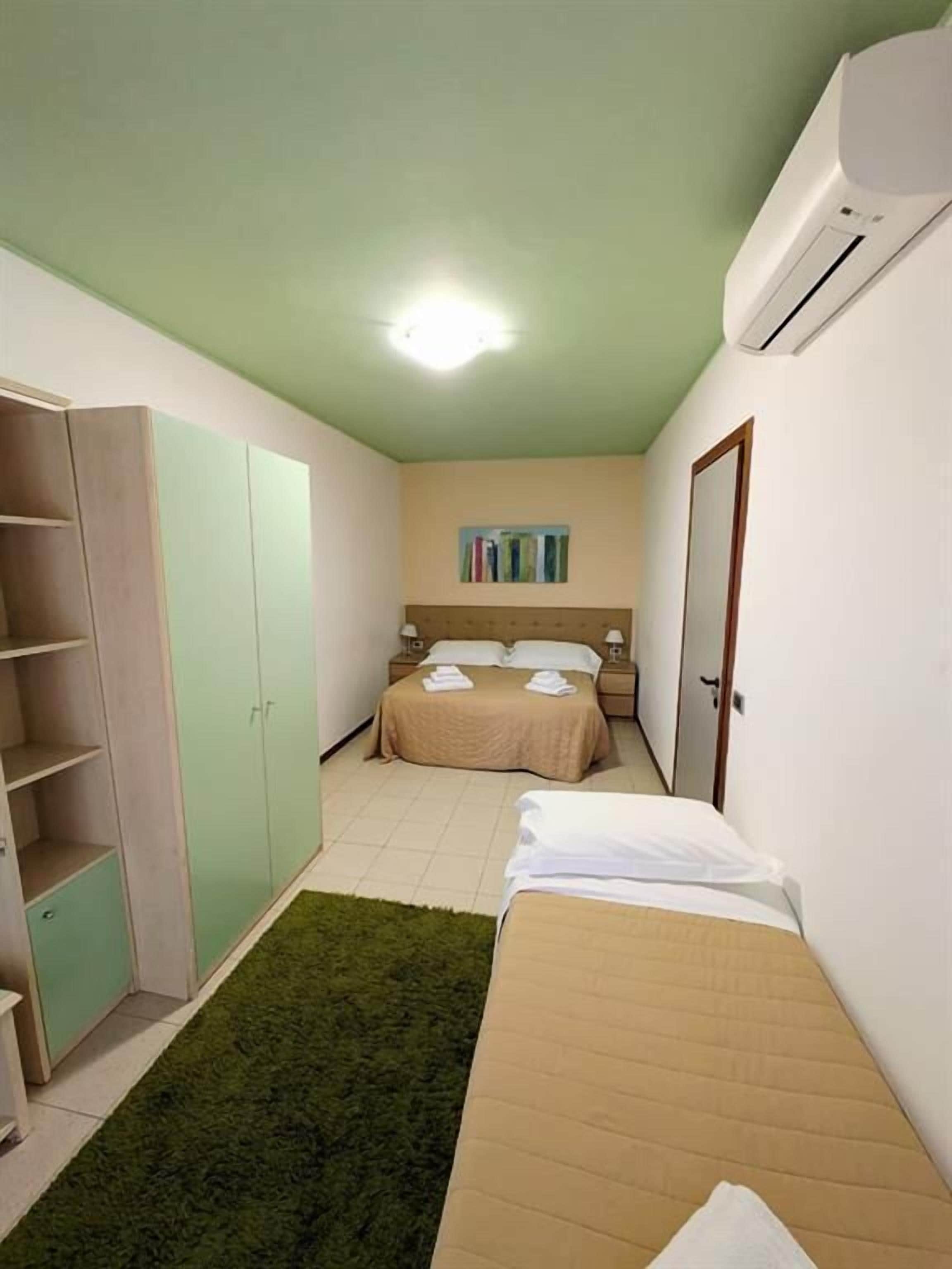 Ein kleiner, gut beleuchteter Raum mit einem Bett, einem Kleiderschrank und einem Nachttisch.