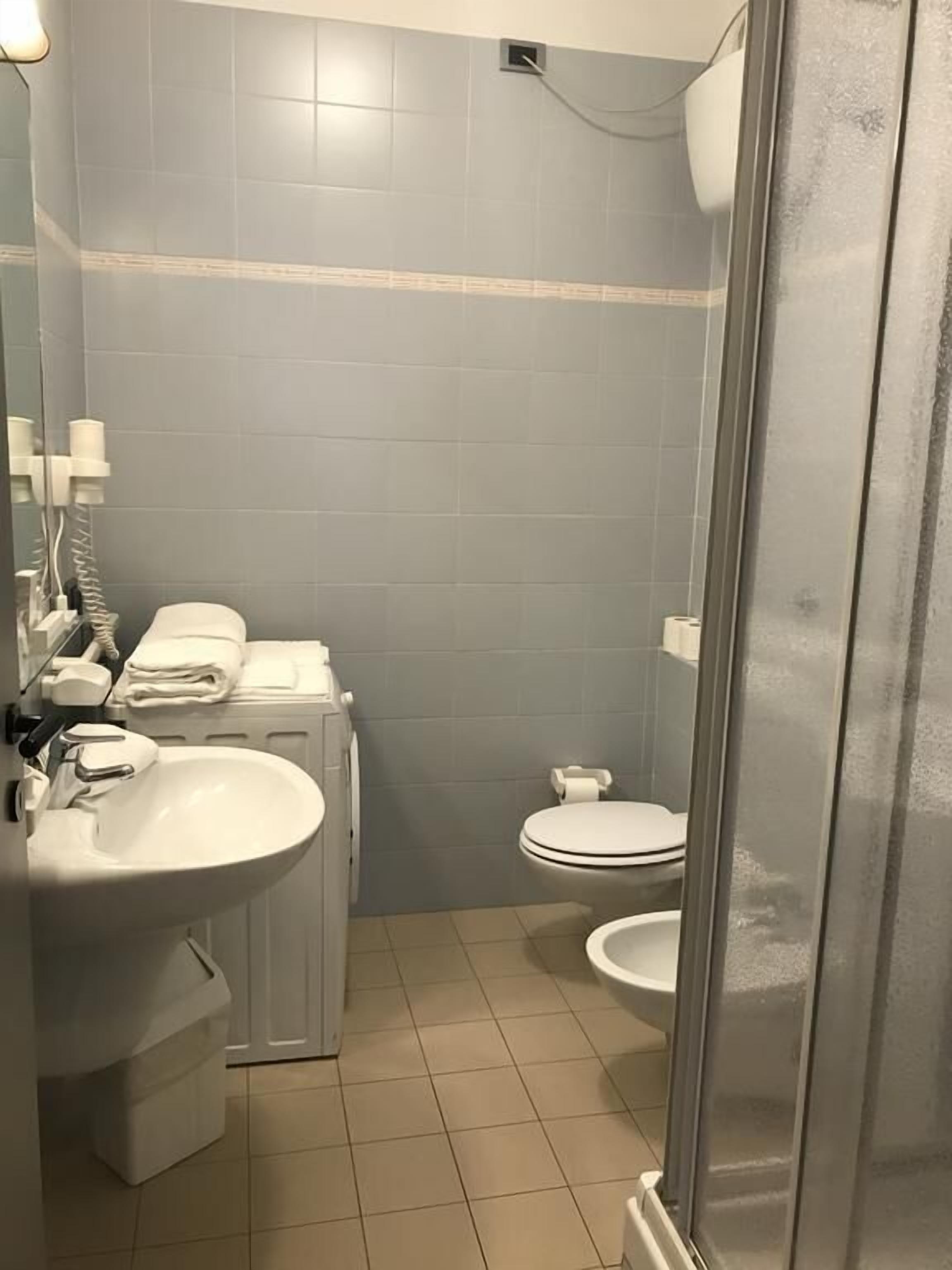 A compact bathroom with a sink, toilet, and shower area.