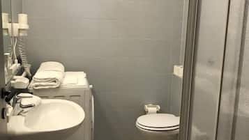 A compact bathroom with a sink, toilet, and shower area.