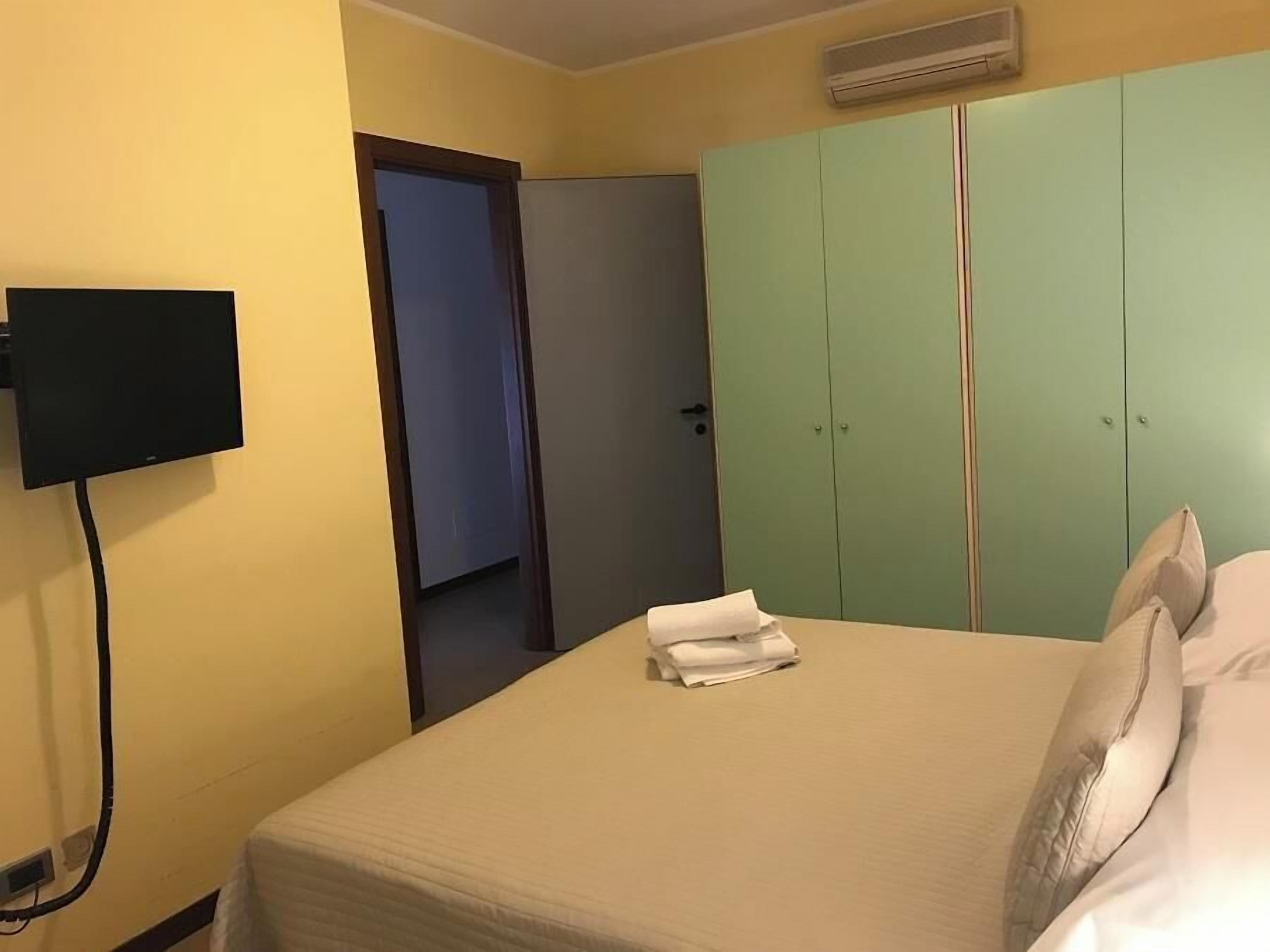 Una habitación de hotel con una cama, un televisor instalado en la pared y un armario.