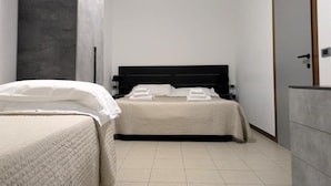 Un dormitorio moderno con dos camas, un armario y un cabecero oscuro.