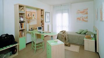 A bedroom with a desk, chair, bed, and a wardrobe.