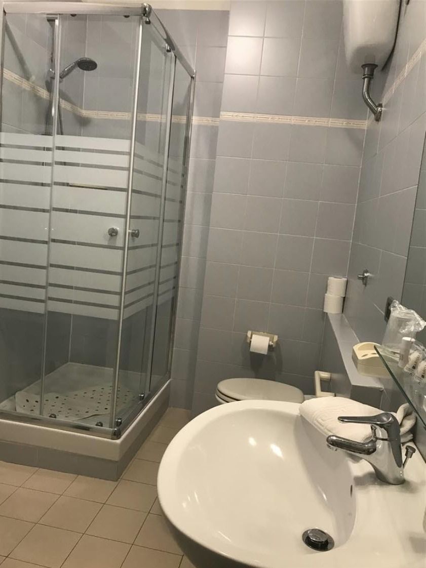 Ein Badezimmer mit einer Duschkabine, einem weißen Waschbecken und einer Toilette.