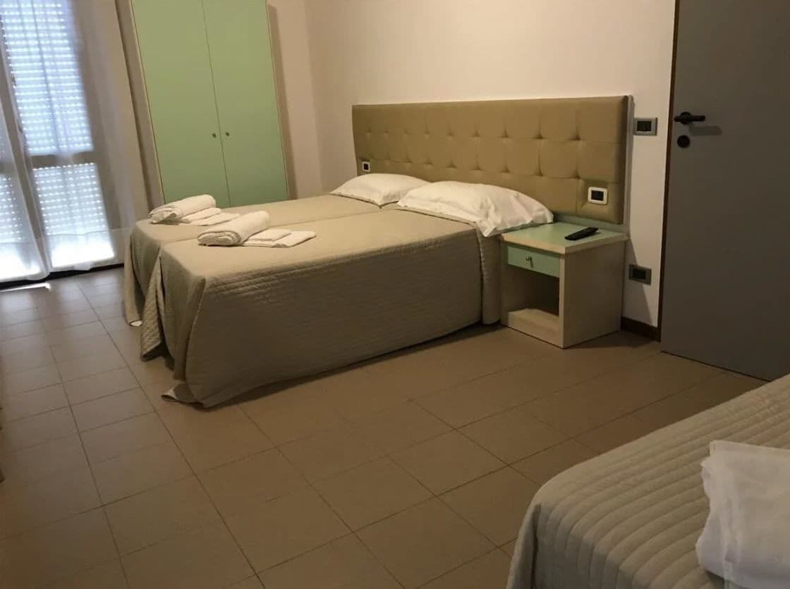 Een hotelkamer met een groot bed, een nachtkastje en een groene garderobe.