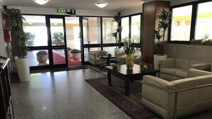 Un vestíbulo con mostrador de recepción, zona de estar y grandes ventanales.