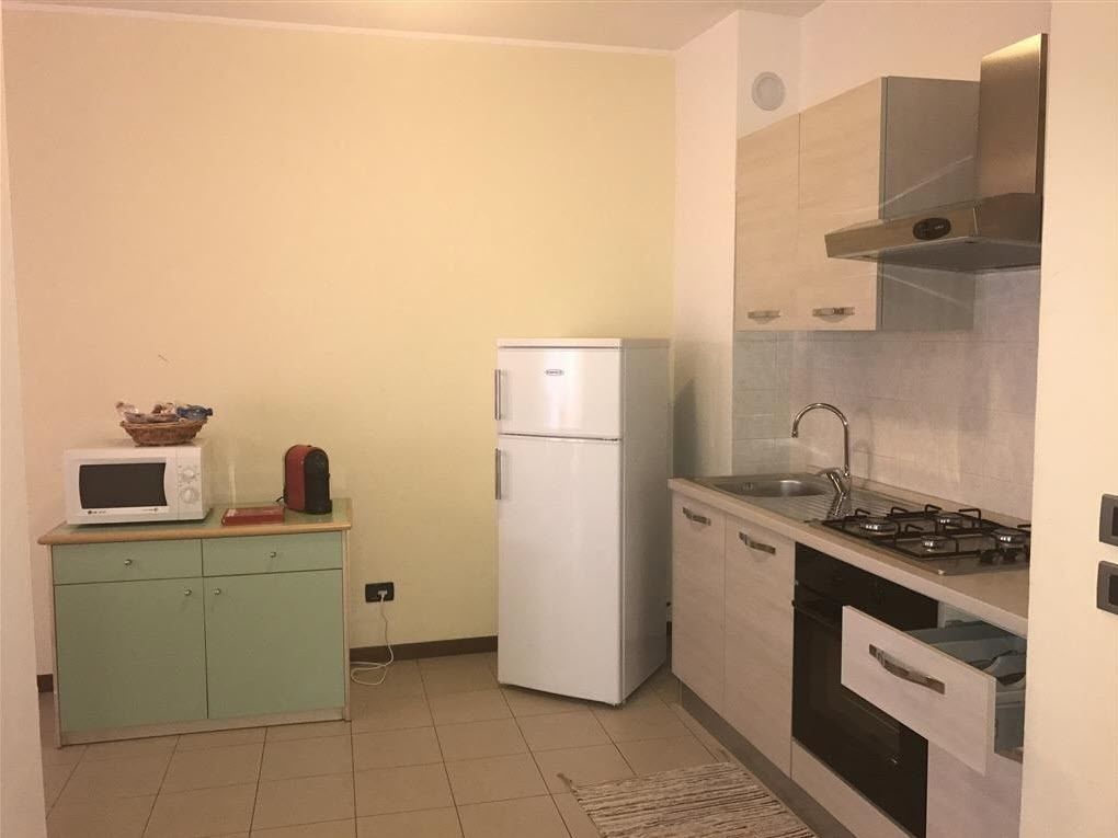 A compact kitchen with a microwave, refrigerator, stove, and cabinets.