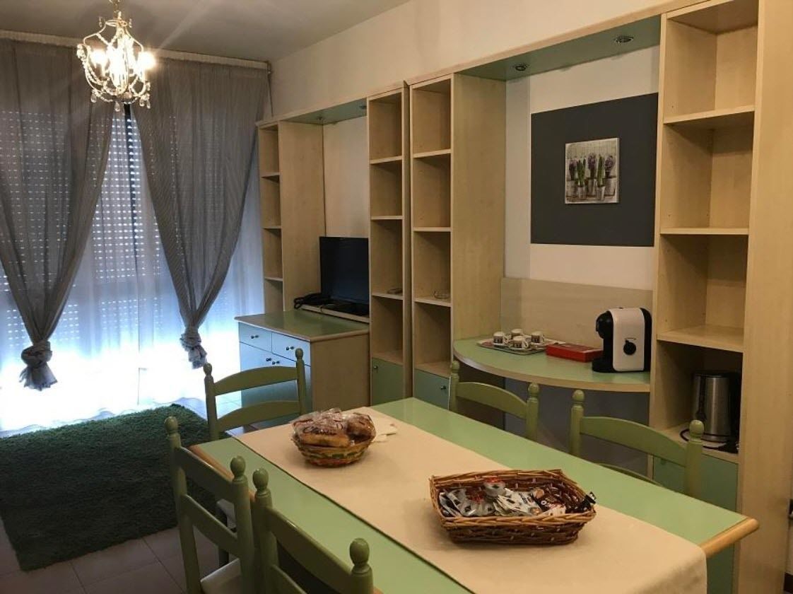 A dining area with a table, chairs, and shelves with various items.