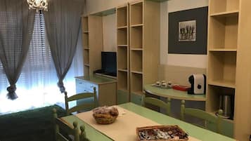 A dining area with a table, chairs, and shelves with various items.