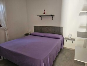 A bedroom with a bed, a nightstand, a wall-mounted shelf, and a bedside table. - Camping Ulisse (Lamezia Terme)