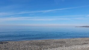 A coastal landscape with a pebbly beach and calm sea under a clear sky. - Camping Ulisse (Lamezia Terme)