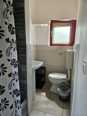 A compact bathroom with a toilet, sink, and window. - Camping Ulisse (Lamezia Terme)