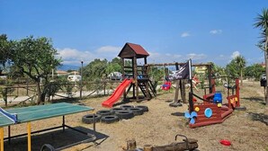 A playground with a slide, climbing structure, and a ping pong table. - Camping Ulisse (Lamezia Terme)