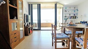 A modern living room with a TV, wooden cabinet, and a dining area with chairs and a table. - Lovely apartment for 4 people with A/C, WIFI, TV and terrace (Torroella De Montgrí)