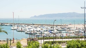 A marina with numerous boats docked, a beach in the background, and mountains in the distance. - Lovely apartment for 4 people with A/C, WIFI, TV and terrace (Torroella De Montgrí)