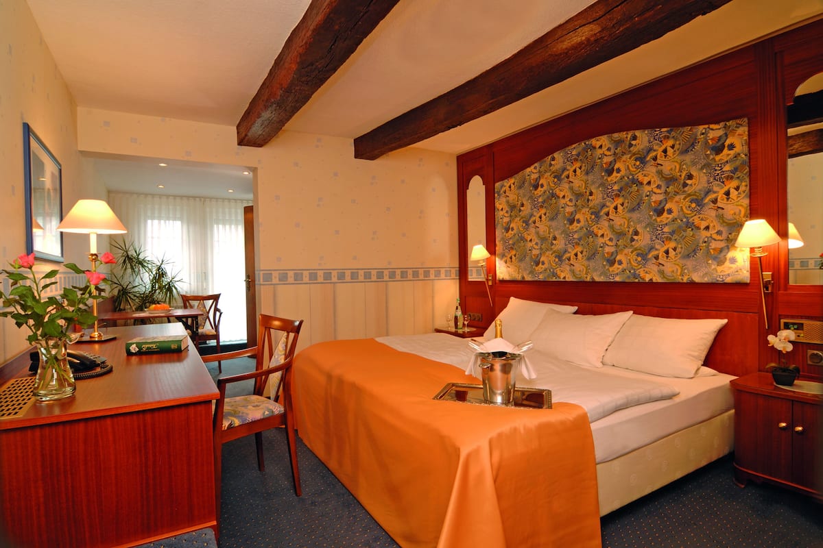 A hotel room with a bed, desk, chair, and a large mirror.