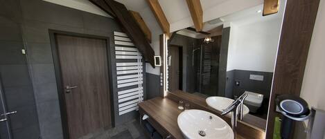A modern bathroom with a large mirror, a sink, and a hairdryer.