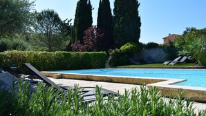 A swimming pool with lounge chairs and a stone deck. - La Bastide Bleue (Seguret)