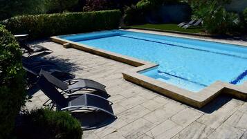 Una piscina al aire libre de temporada, sombrillas