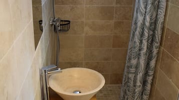 Une salle de bain avec un lavabo beige, une douche et un rideau de douche à motifs.