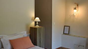 Un dormitorio con una cama, una mesita de noche con una lámpara, una luz empotrada en la pared y un certificado enmarcado.