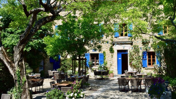 A courtyard with outdoor seating, stone walls, and blue shutters. - La Bastide Bleue (Seguret)