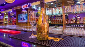 A bar area with a bottle of champagne and glasses on the counter. - IBD International Hotels Limited (Abeokuta)