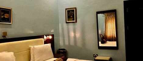 A hotel room with a bed, a nightstand, a mirror, and a framed picture on the wall.