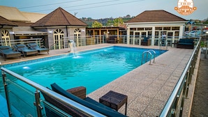 A swimming pool with lounge chairs and a small waterfall feature. - IBD International Hotels Limited (Abeokuta)