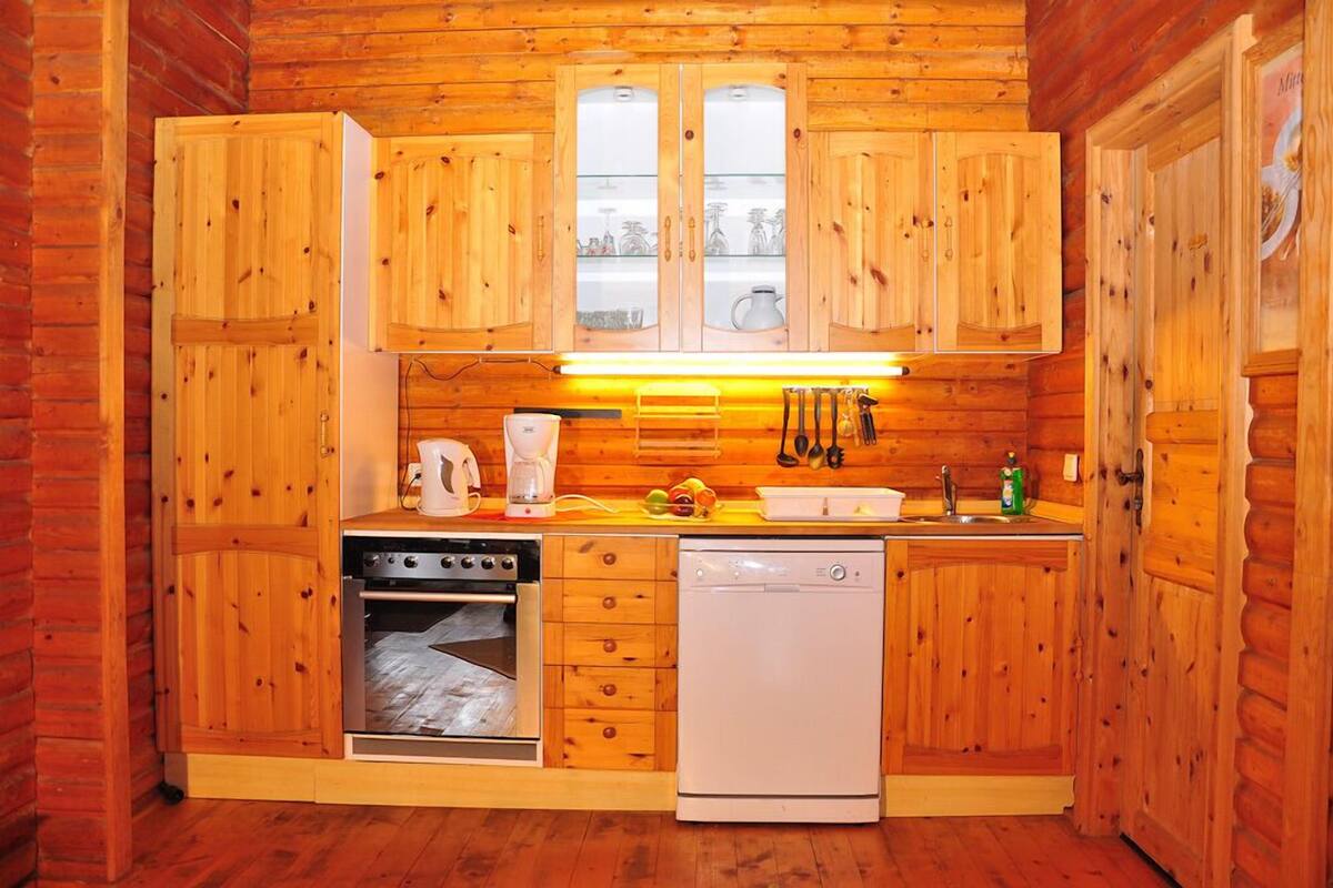 Een compact houten keuken met inbouwkasten, een vaatwasser, een oven en een koffiezetapparaat.