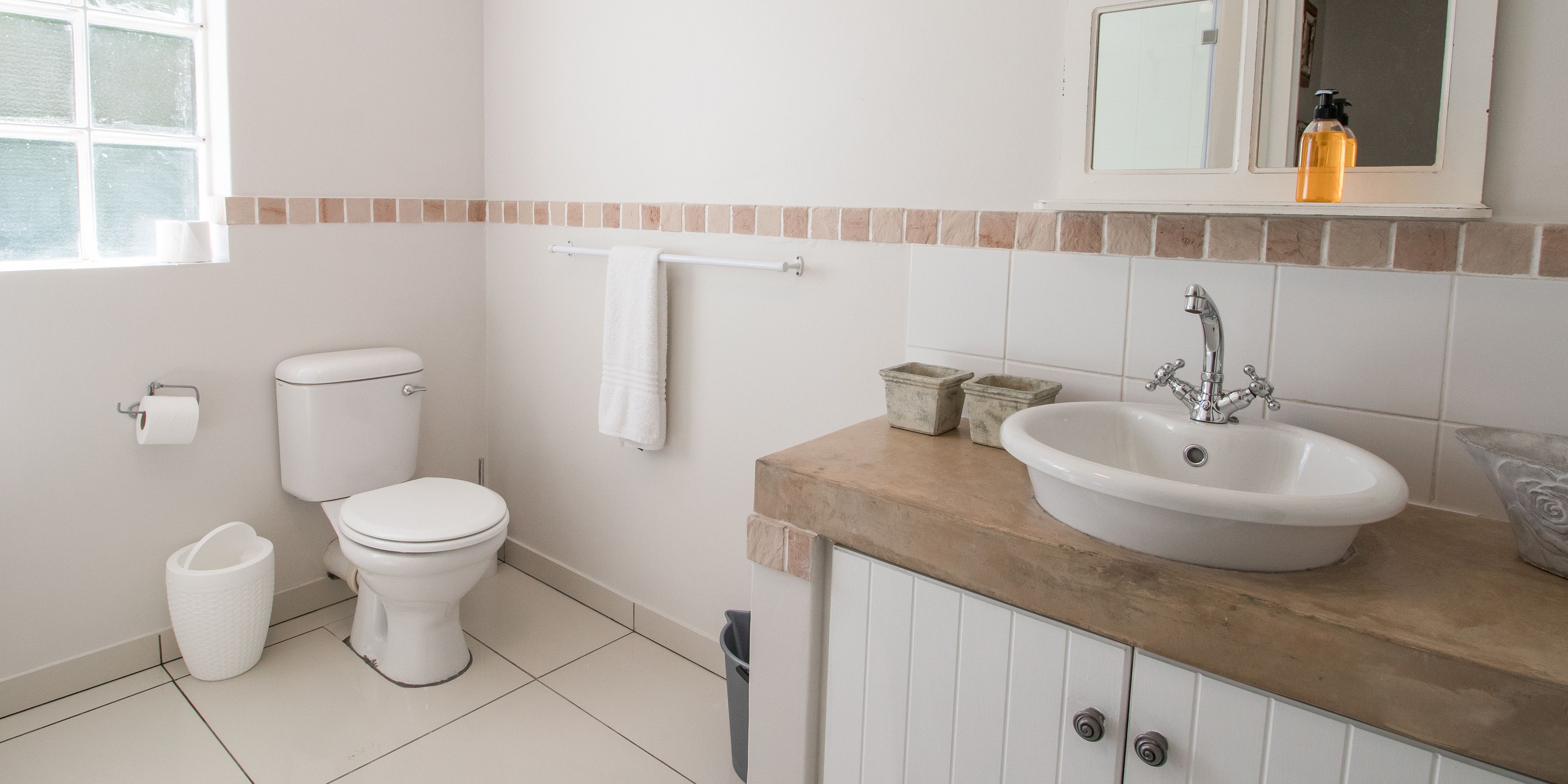 A bathroom with a toilet, sink, and mirror.