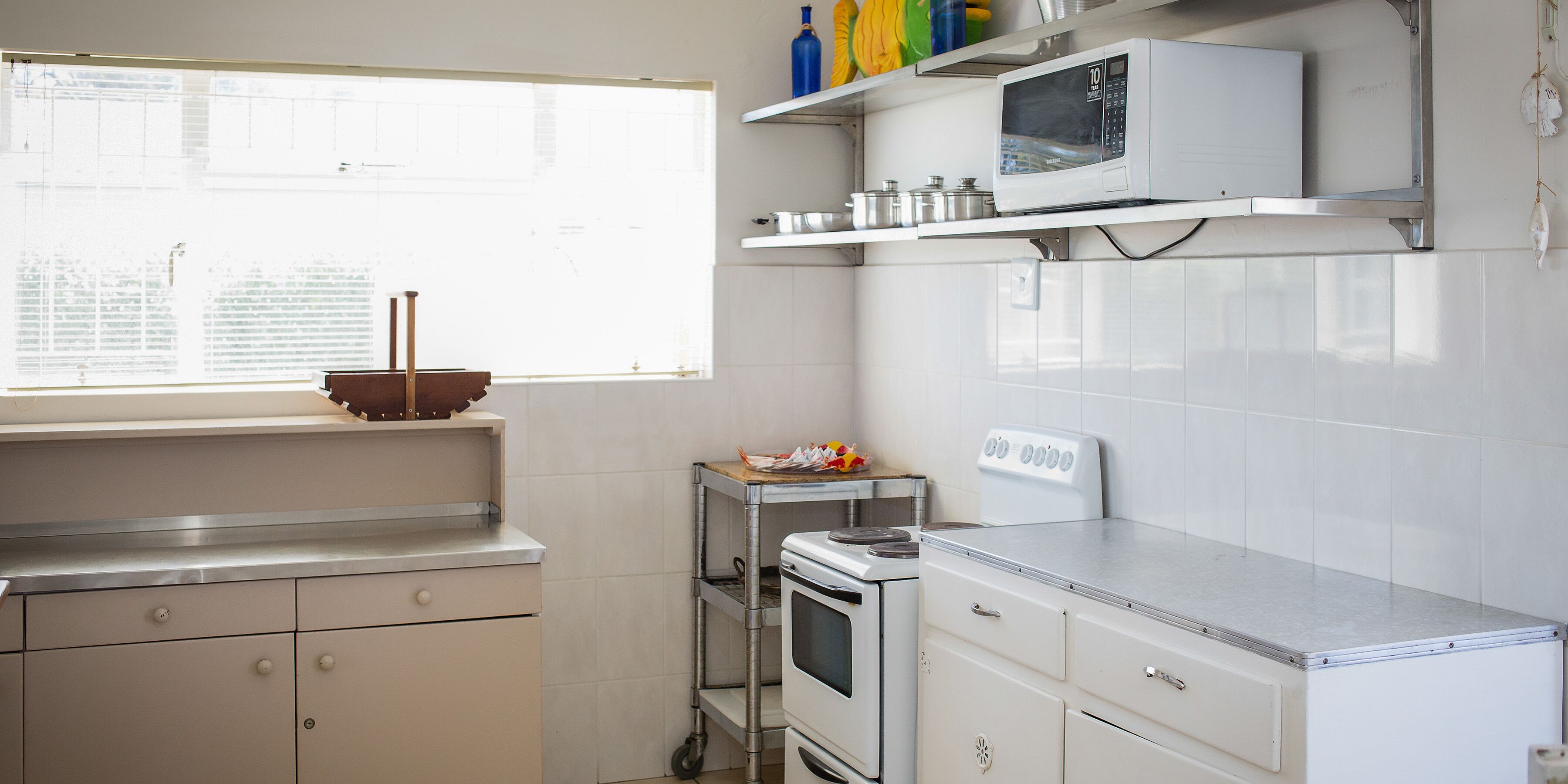 Una cocina con estufa, microondas y armarios.