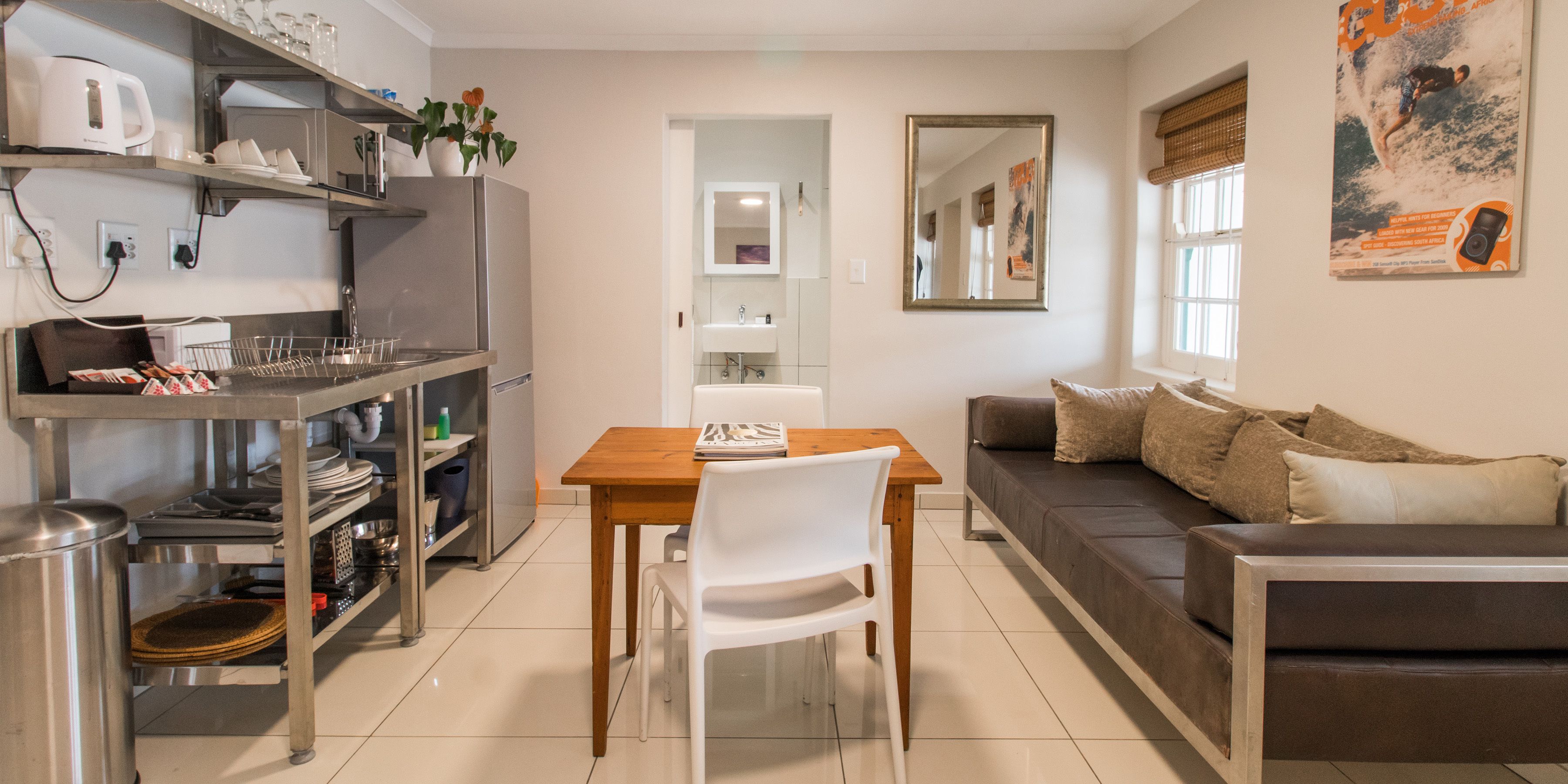 Una cocina moderna con una mesa de comedor y sillas, un sofá gris y un espejo grande en la pared.