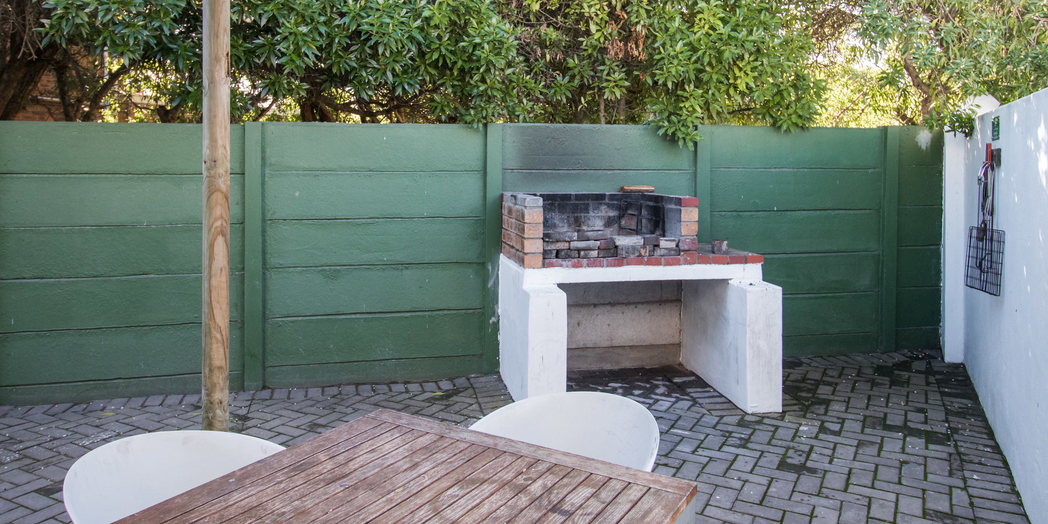 A small outdoor seating area with a brick fireplace, green walls, and a brick floor.