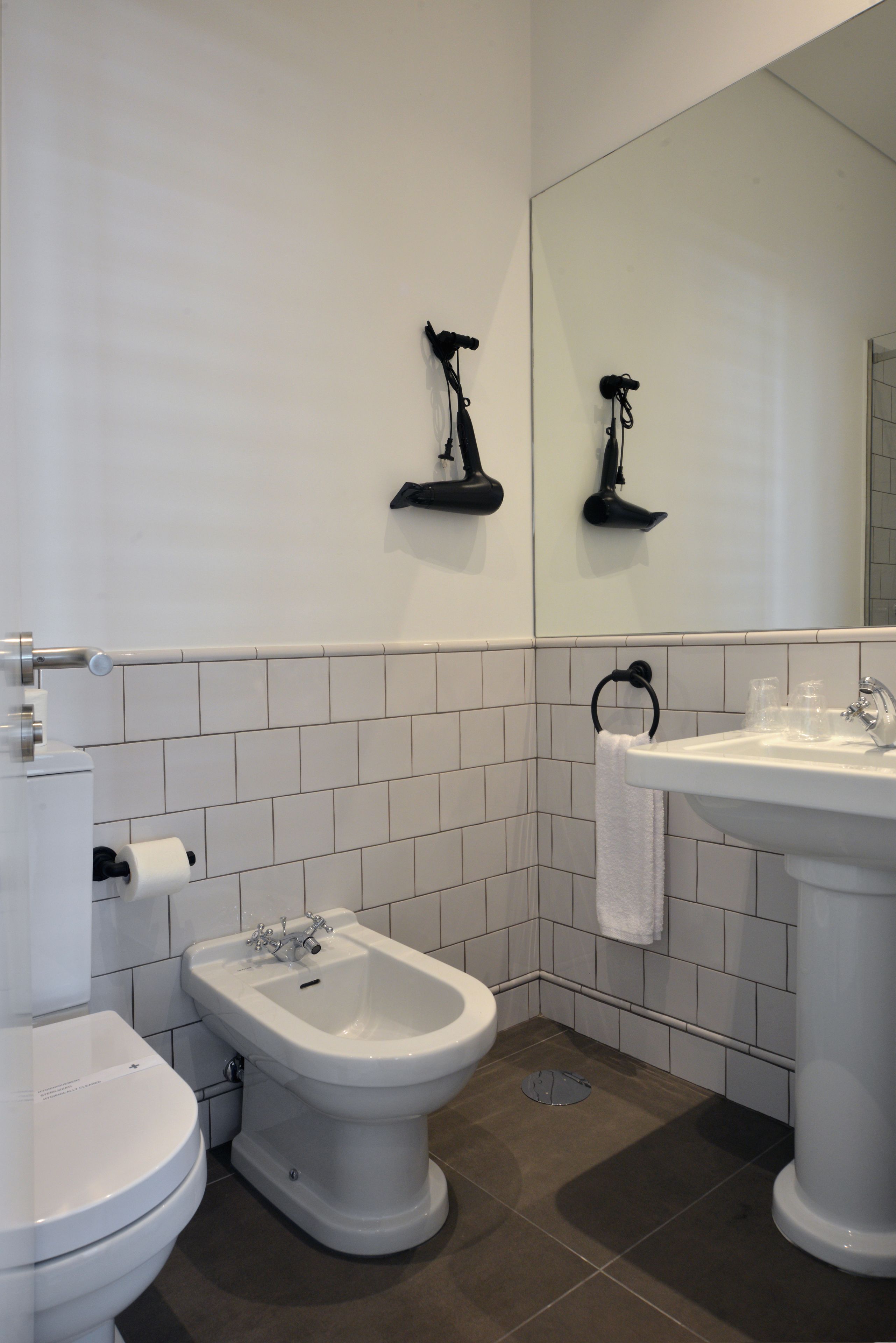Un baño con inodoro, bidé, lavamanos y espejo.