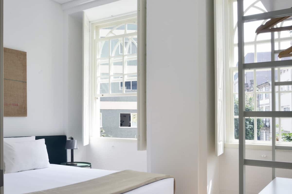 A bedroom with a bed, a desk, and a window.