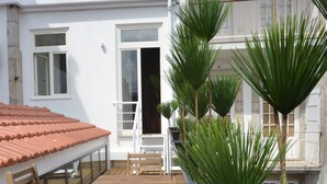A wooden deck with a table and chairs, surrounded by potted plants. - Spot Apartments Casa Januario (Porto)
