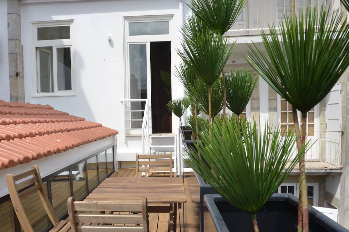 A wooden deck with a table and chairs, surrounded by potted plants.