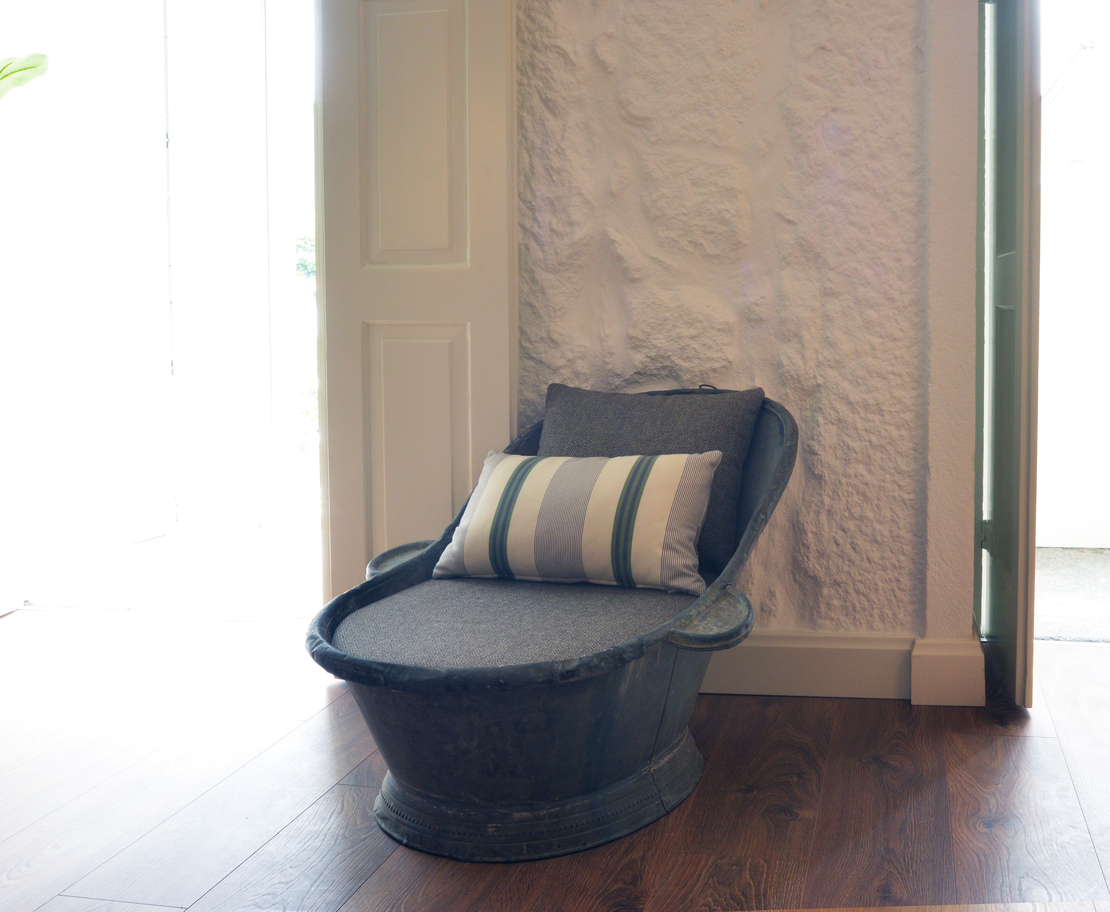 A chair with a cushion and a textured wall in the background.