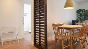 A dining area with a wooden table and chairs, a hanging light fixture, and a wooden partition. - Spot Apartments Casa Januario (Porto)