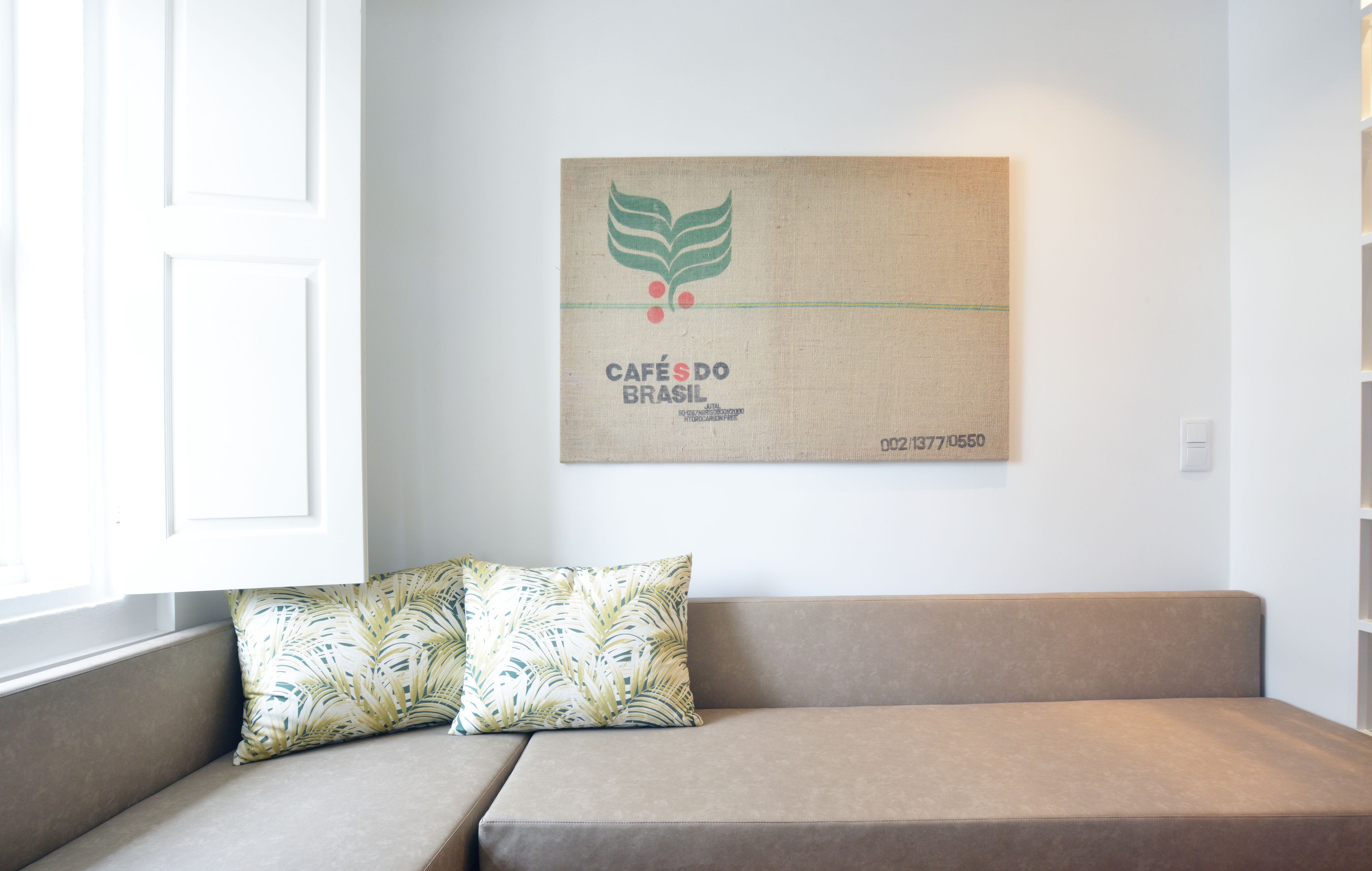 A modern living room with a beige sofa, a patterned pillow, and a wall-mounted artwork featuring a logo and text.