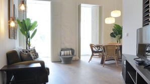 A spacious living area with a sofa, a dining table with chairs, and hanging pendant lights. - Spot Apartments Casa Januario (Porto)