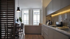 A modern kitchen with grey cabinets, a wooden dining table, and a built-in oven. - Spot Apartments Casa Januario (Porto)