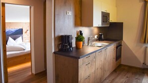 A compact kitchen with wooden cabinets, a microwave, and a coffee maker. - Edelweiss - Wiesenhof (Kaunerberg)