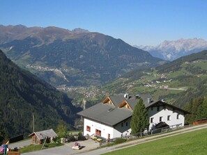 Un pueblo de montaña con un edificio blanco que tiene un balcón y un letrero que dice 'Wienerhaus'.