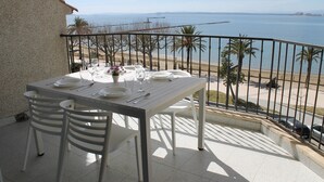 Een balkon met een eettafel, met uitzicht op een strand en de zee.