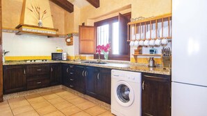 Una cocina con armarios de madera oscura, una lavadora, un microondas y un lavabo.