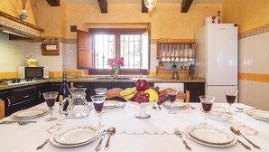 Una cocina con mesa y sillas dispuestas para una comida, un refrigerador y una ventana con vistas.