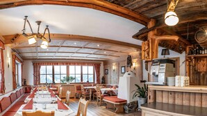 Een restaurant met houten inrichting, een lange gedeelde tafel en een keukenhoek.