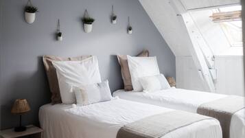 A bedroom with two beds, a bedside table with a lamp, and wall-mounted planters.