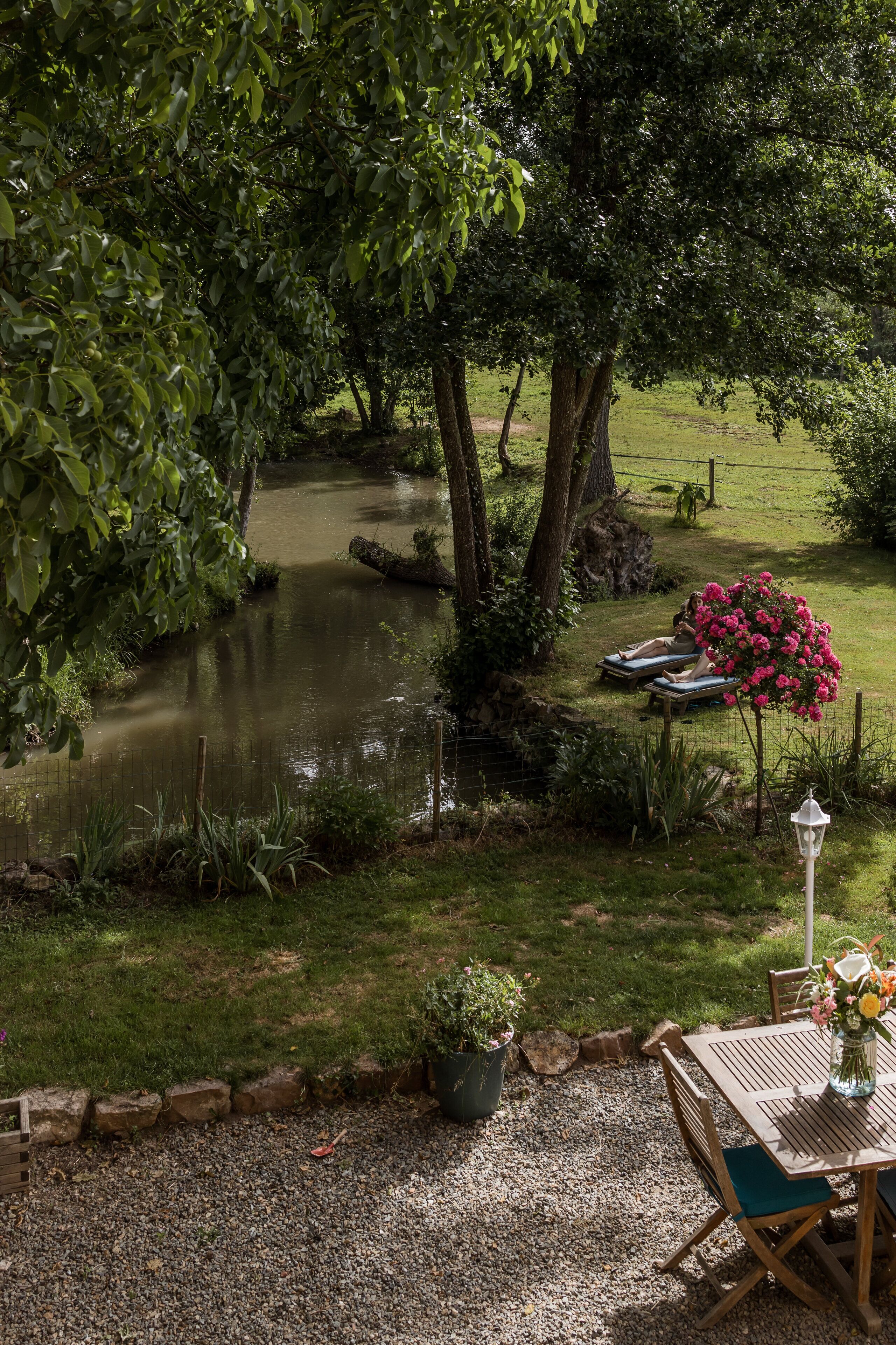 A garden with a pond, a table with chairs, and a potted plant.